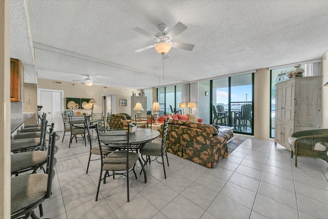 tiled dining space featuring floor to ceiling windows, ceiling fan, and a textured ceiling