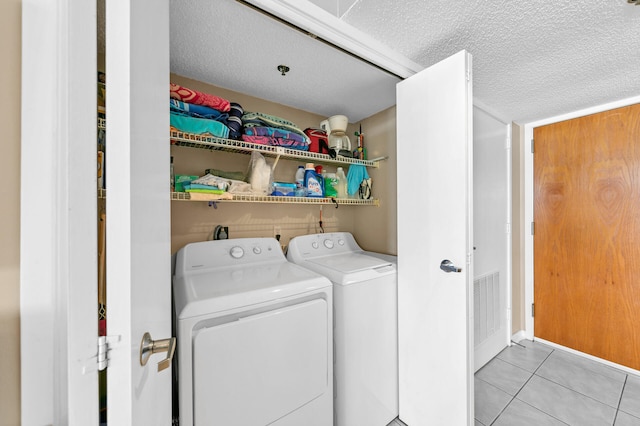 laundry room with a textured ceiling, hookup for an electric dryer, light tile flooring, and washer and dryer