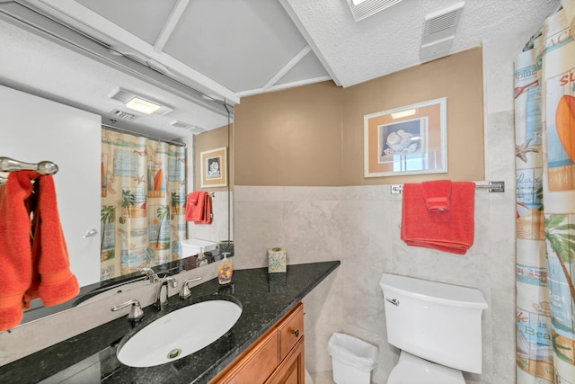 bathroom featuring vanity, toilet, tile walls, and a textured ceiling