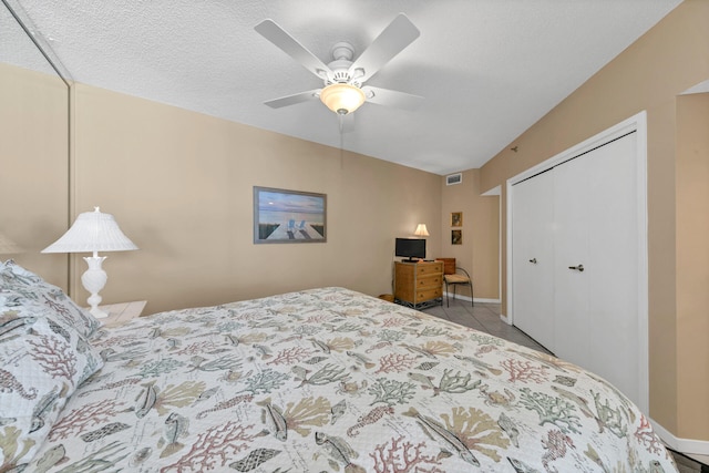 bedroom with a closet, a textured ceiling, ceiling fan, and light tile flooring