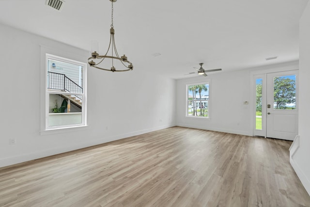 interior space featuring visible vents, light wood-style flooring, baseboards, and ceiling fan with notable chandelier