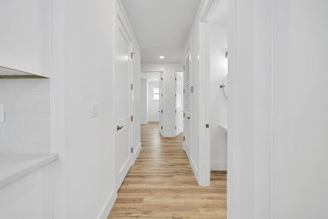 corridor with light wood-style floors, baseboards, and recessed lighting