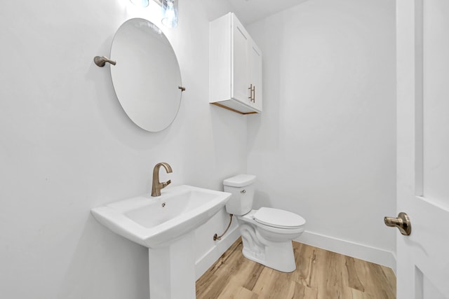 bathroom with baseboards, a sink, toilet, and wood finished floors