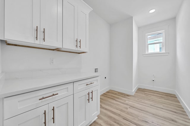 bar featuring white cabinetry, light stone countertops, and light wood-type flooring