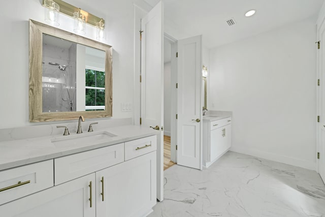 full bathroom with marble finish floor, two vanities, a sink, and a marble finish shower