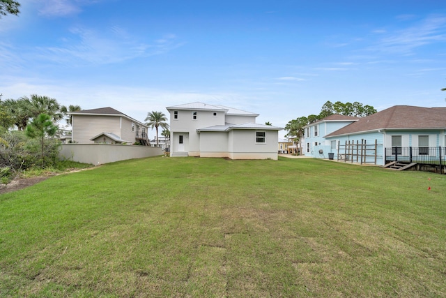 rear view of property featuring fence and a yard