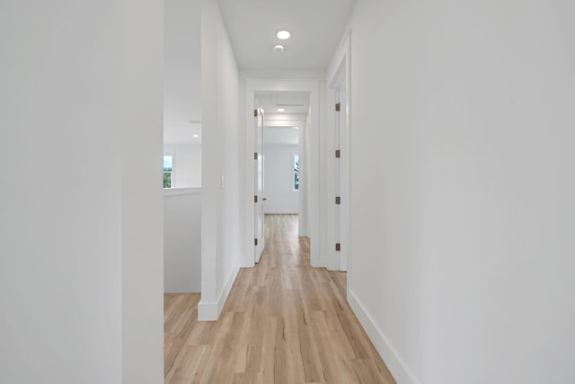 corridor with light wood-type flooring, baseboards, and recessed lighting