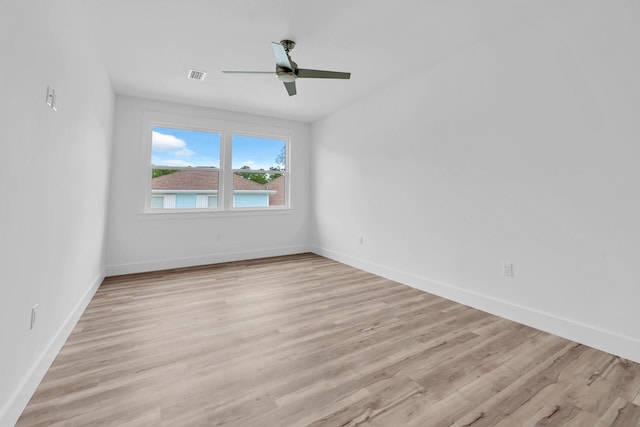 spare room featuring light wood-type flooring, baseboards, visible vents, and a ceiling fan