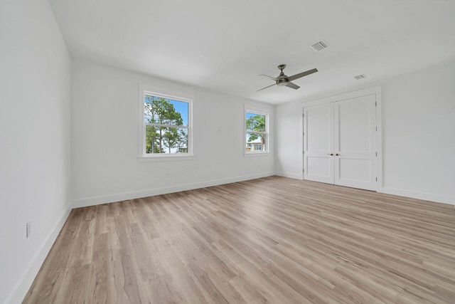 unfurnished bedroom with light wood finished floors, a closet, visible vents, a ceiling fan, and baseboards