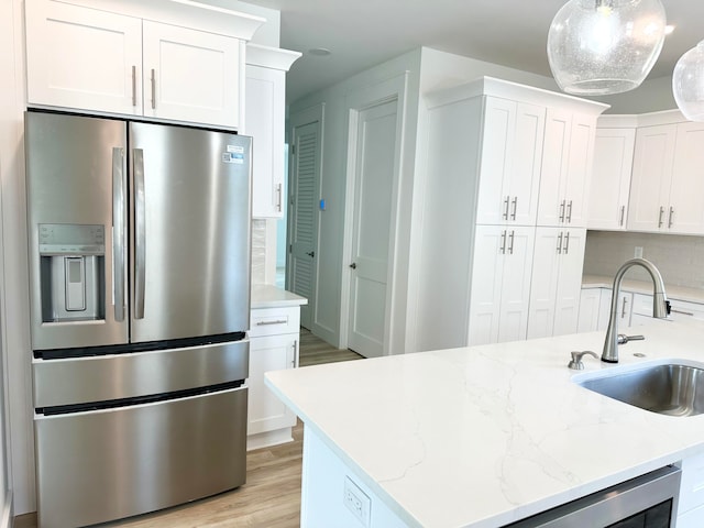 kitchen with pendant lighting, sink, stainless steel refrigerator with ice dispenser, light hardwood / wood-style flooring, and white cabinetry