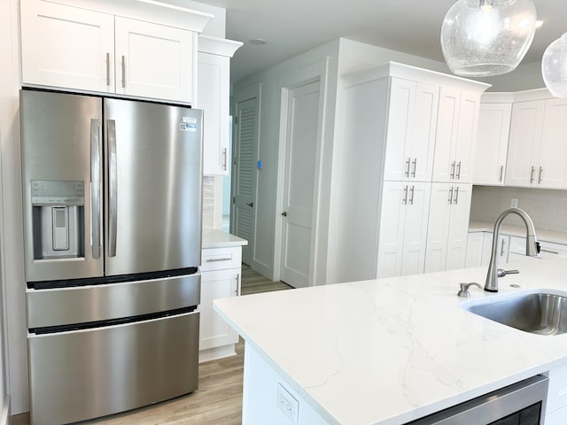 kitchen with white cabinets, hanging light fixtures, a sink, and stainless steel fridge with ice dispenser