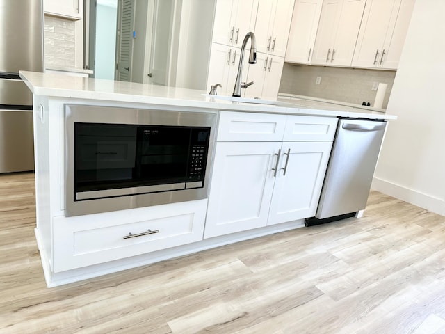 kitchen featuring appliances with stainless steel finishes, light wood-type flooring, light countertops, and white cabinetry