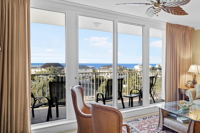 sunroom / solarium featuring ceiling fan and a water view