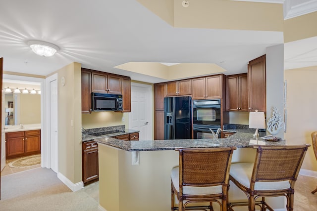 kitchen with kitchen peninsula, crown molding, dark stone countertops, a breakfast bar, and black appliances