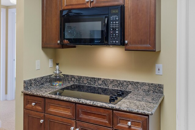 kitchen with stone counters and black appliances