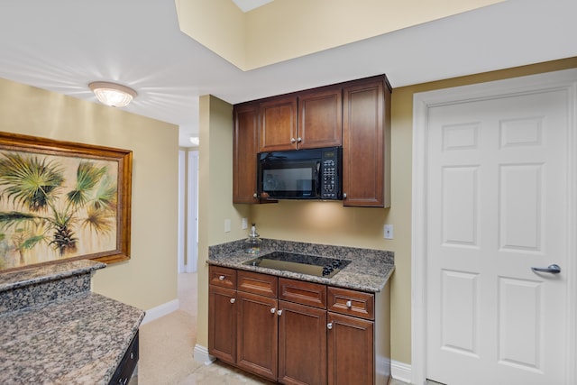 kitchen featuring dark stone counters and black appliances