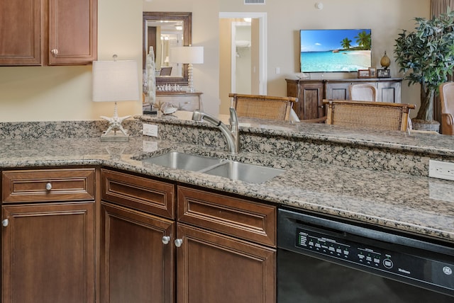 kitchen with black dishwasher, light stone counters, and sink