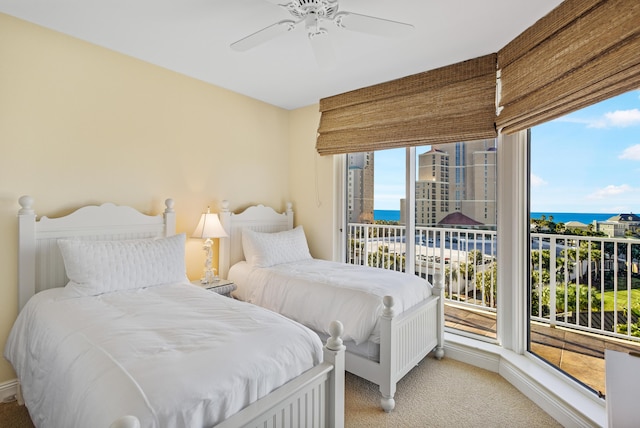 carpeted bedroom featuring access to outside, ceiling fan, and a water view