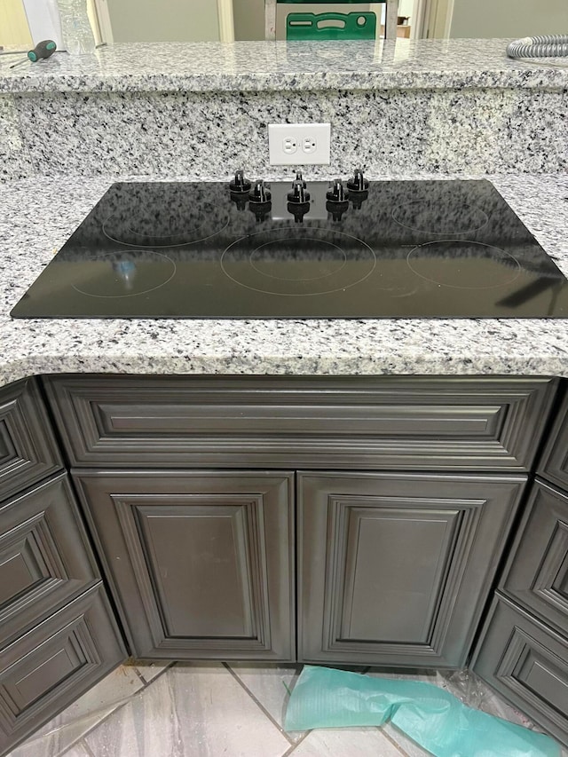 interior details with black electric stovetop and light stone countertops