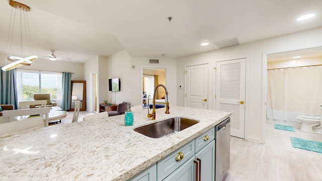 kitchen featuring pendant lighting, sink, stainless steel dishwasher, light stone countertops, and light hardwood / wood-style flooring