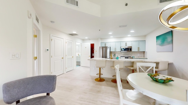 kitchen with appliances with stainless steel finishes, a kitchen breakfast bar, light stone countertops, and decorative backsplash