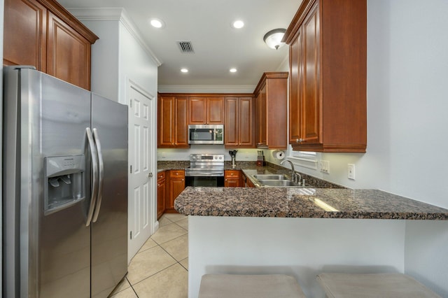 kitchen with light tile floors, sink, stainless steel appliances, kitchen peninsula, and dark stone countertops