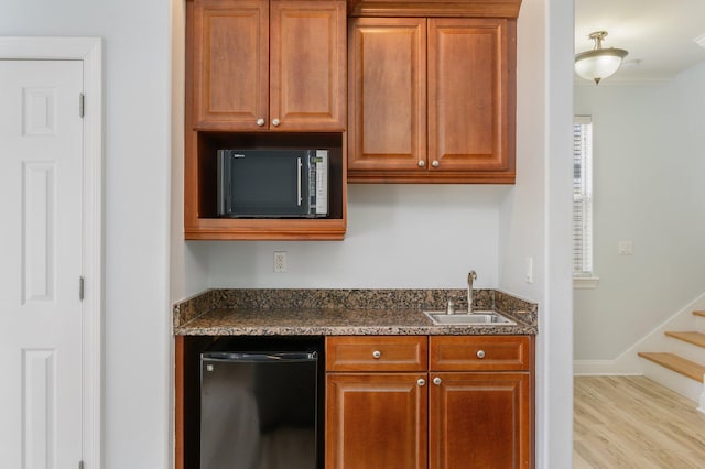 kitchen featuring sink, light hardwood / wood-style floors, black appliances, and dark stone counters