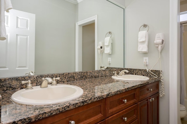 bathroom featuring double sink, toilet, oversized vanity, and crown molding