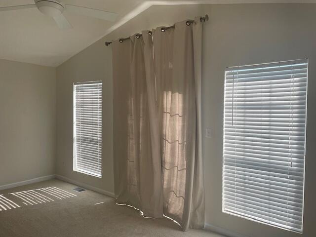 carpeted spare room with ceiling fan and vaulted ceiling