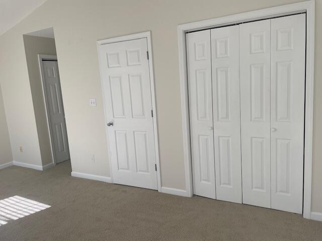 unfurnished bedroom with light colored carpet and lofted ceiling