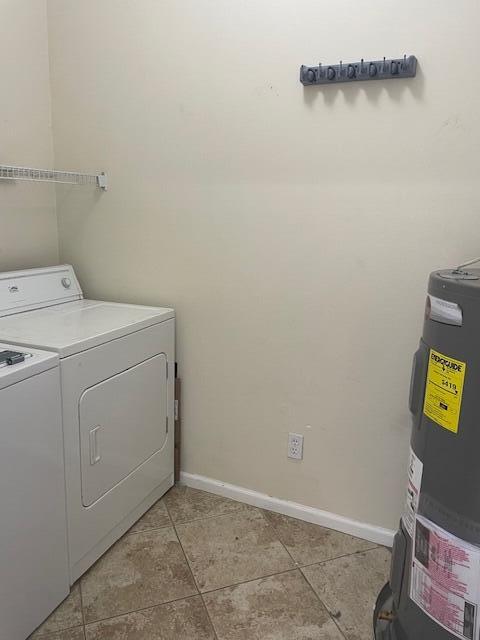 washroom featuring water heater, light tile floors, and washing machine and clothes dryer