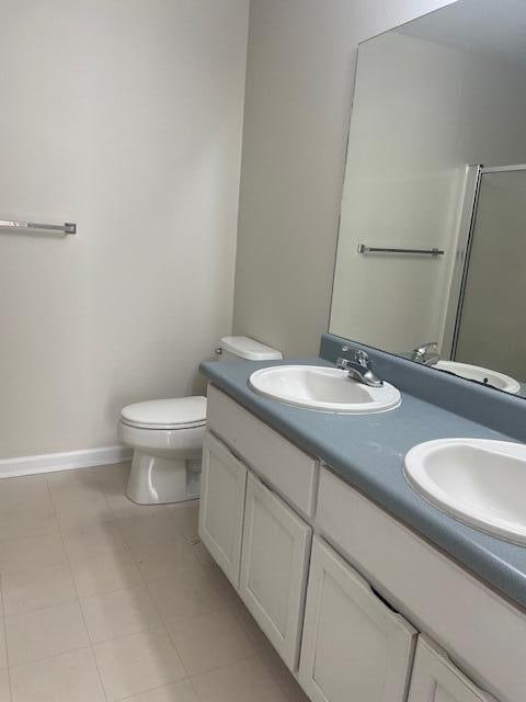 bathroom featuring double sink vanity, toilet, and tile flooring