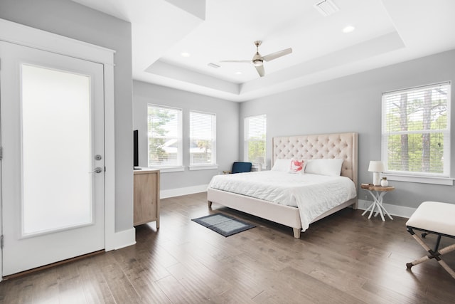 bedroom with ceiling fan, a raised ceiling, and dark hardwood / wood-style floors