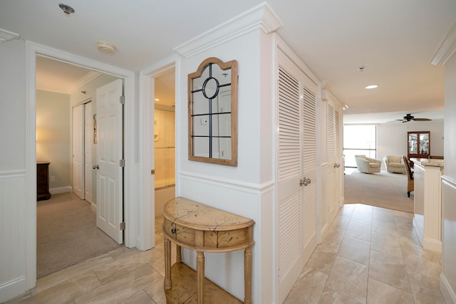 hallway with light colored carpet and crown molding