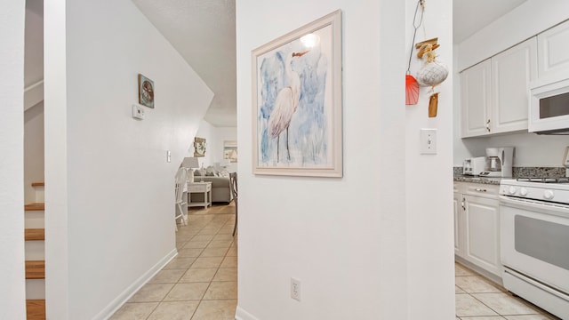 kitchen featuring white cabinets, white appliances, and light tile flooring