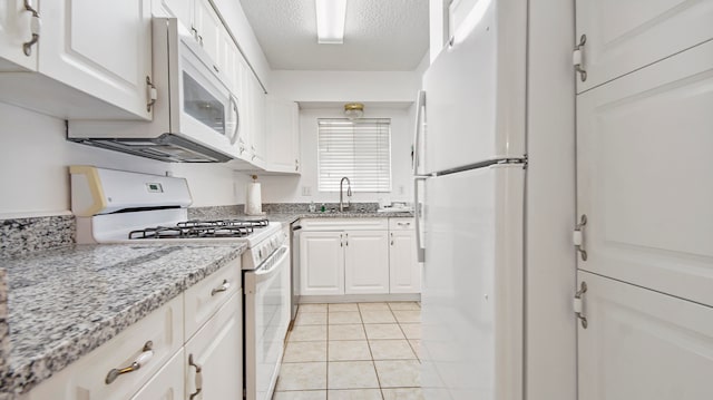 kitchen with white cabinets, sink, white appliances, and light tile flooring