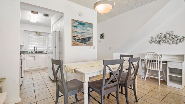 dining room with sink, a textured ceiling, and light tile floors