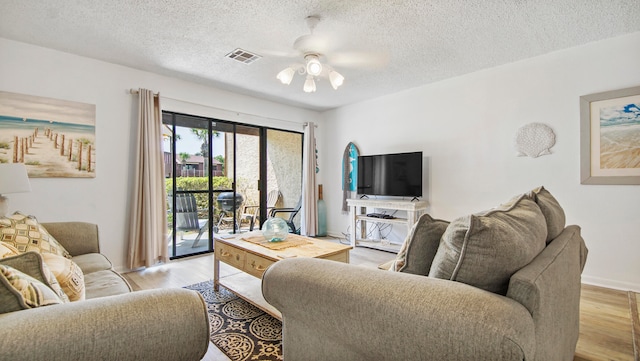 living room with light hardwood / wood-style flooring, ceiling fan, and a textured ceiling