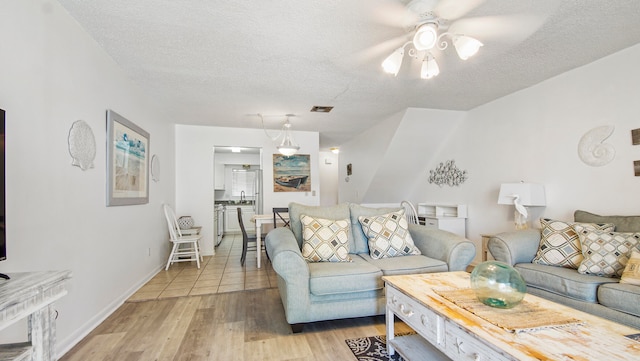 tiled living room featuring sink, ceiling fan, and a textured ceiling