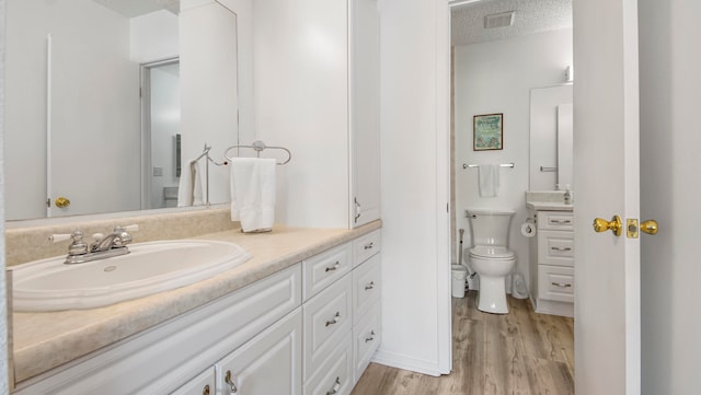 bathroom with vanity, hardwood / wood-style flooring, toilet, and a textured ceiling