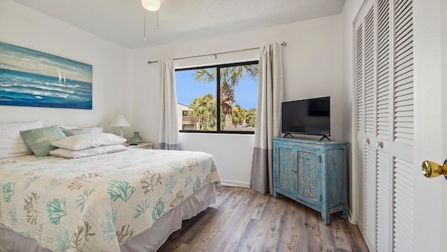 bedroom with wood-type flooring, ceiling fan, and a closet