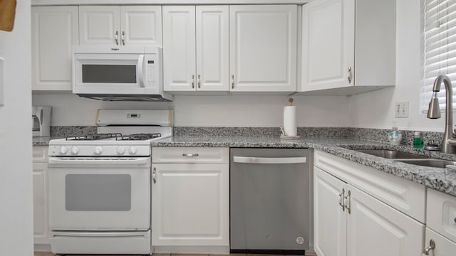 kitchen with sink, white appliances, white cabinetry, and light stone countertops