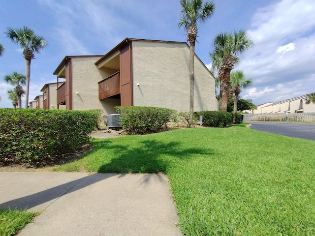 view of side of home featuring a yard, central AC, and a balcony