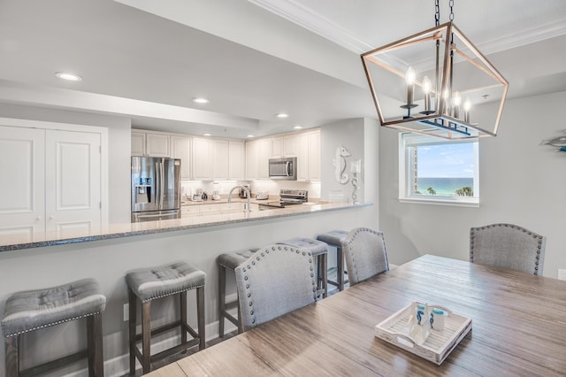 kitchen featuring appliances with stainless steel finishes, light stone countertops, pendant lighting, and an inviting chandelier