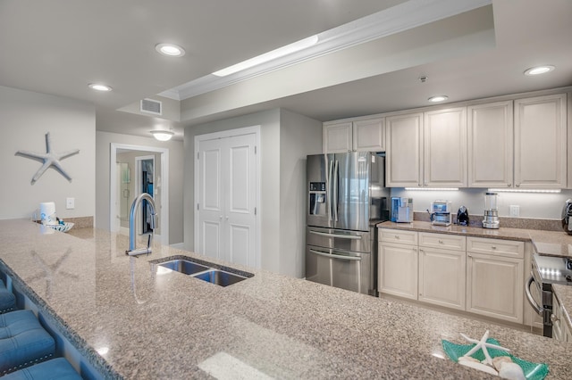 kitchen with light stone counters, kitchen peninsula, a breakfast bar area, sink, and stainless steel fridge