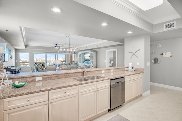 kitchen with light stone countertops, dishwasher, sink, and a tray ceiling