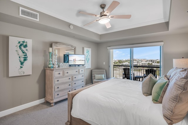 carpeted bedroom with ceiling fan, access to exterior, and a tray ceiling