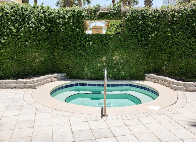 view of swimming pool featuring a hot tub and a patio area