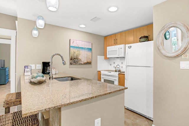 kitchen with a breakfast bar, sink, kitchen peninsula, white appliances, and light stone countertops