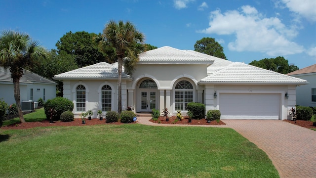 view of front of home with french doors, a garage, central AC, and a front lawn